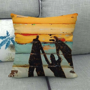 Close-up of linen pillow cover with abstract painted figure art on a grey sofa