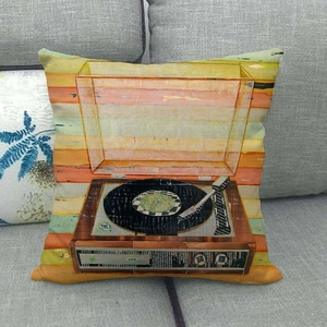 Close-up of linen pillowcase featuring a retro record player print on a gray sofa