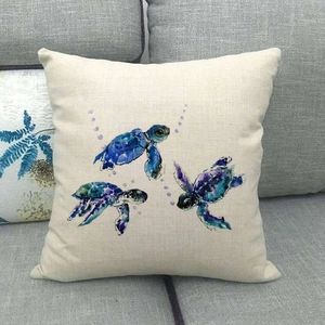 Detail shot of sea turtle watercolor print on textured linen cushion cover on a grey sofa