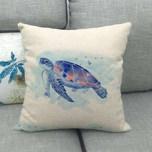 Macro detail of a square linen cushion cover featuring a watercolor turtle print on a sofa