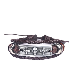 Detail of men's brown braided leather bracelet with silver skull and cross motif