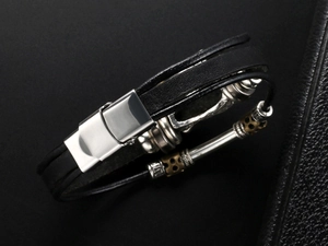 Close-up of men's black leather bracelet with vintage metal beads and snap clasp