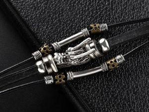 Macro detail of punk leather bracelet showing a silver dragon head and metallic charms