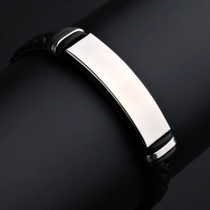Détail de la plaque en acier inoxydable poli sur le bracelet en cuir tressé noir