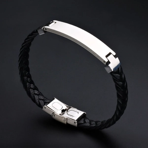 Detailed close-up of stainless steel clasp engraving on black braided leather bracelet