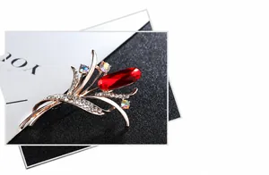 Detailed macro view of a gold-plated flower brooch with large red crystal and rhinestones