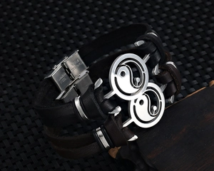 Macro detail of men's leather bracelet with stainless steel Yin Yang charm and buckle