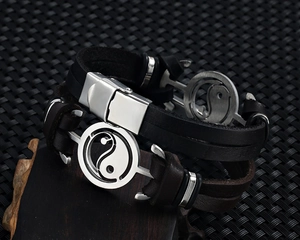 Macro detail of men's leather bracelets featuring stainless steel Yin Yang symbols