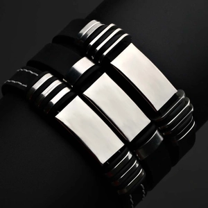Detail of three black silicone and stainless steel bracelets for men with polished metal plates
