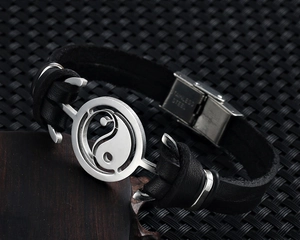 Macro detail of stainless steel clasp and yin yang symbol on black leather bracelet