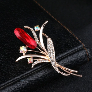Elegante rotgoldene Tulpenbrosche mit rotem Kristall auf schwarzem Lederhintergrund