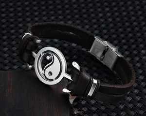 Detail of vintage Yin Yang charm on braided leather bracelet with stainless steel clasp