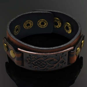 Detail of vintage punk leather bracelet with celtic metal plate and snap closure