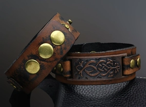 Close-up of vintage wide leather bracelets with brass rivets and celtic engraved plates