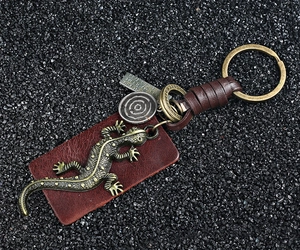 Detail of vintage bronze gecko keychain with leather strap and engraved metal tags