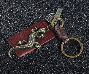 Detail of vintage gecko lizard keychain with bronze metal and braided leather texture