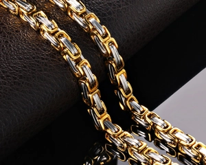 Macro view of two-tone Byzantine steel chain showing interlocking gold and silver links