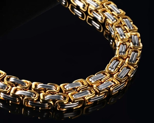 Macro shot of two-tone gold and silver rectangular link chain in polished steel