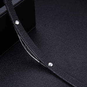 Macro view of black litchi grain leather bracelet with silver rivets and metal accents