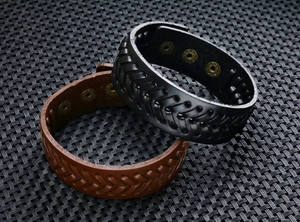Detail von breiten Herren-Lederarmbändern in Schwarz und Braun mit gewebtem V-Muster