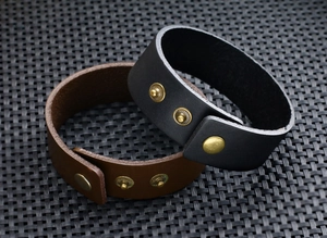 Detail van zwarte en bruine brede leren armbanden met metalen drukknopsluitingen