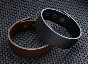 Detail van de brede zwart en bruin lederen armbanden met metalen drukknopsluitingen