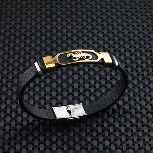 Detail of a black leather men's bracelet with a golden scorpion motif and stainless steel clasp