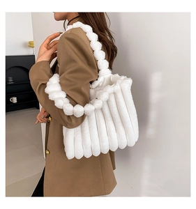 Close-up of fluffy white faux fur tote bag with plush ball handle worn by a model