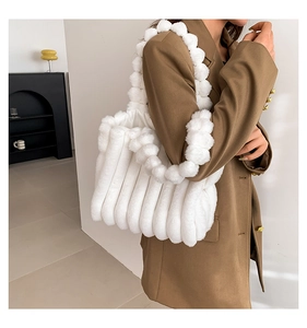 Detail of white faux fur tote bag with textured stripes and plush ball handle design