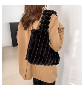 Detail of black faux fur tote bag with plush ball shoulder strap and ribbed texture