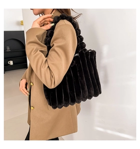 Detail of black faux fur tote bag with striped quilting and decorative fur ball handle