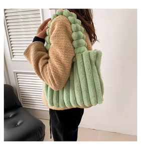 Detail view of grass green faux fur tote bag with textured folds and spherical handle