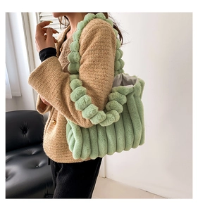 Detail of light green faux fur tote with vertical stripes and plush ball shoulder strap