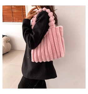 Detail of pink faux fur tote bag featuring vertical stripes and plush ball decoration