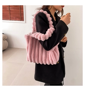 Detailed view of pink plush tote bag with striped texture and fuzzy pom-pom handle