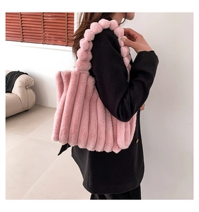 Detail of light pink faux fur tote bag with pleated texture and fuzzy pom-pom handle