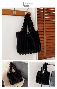 Close-up of black faux fur tote bag with vertical stripes and plush spherical handles