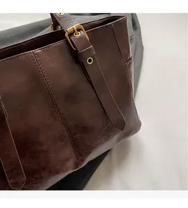 Primer plano de bolso tote marrón vintage con costuras reforzadas y hebillas de metal