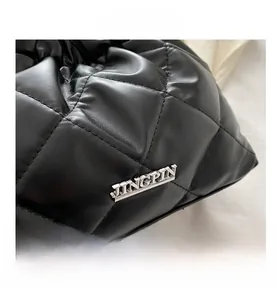 Gros plan sur la texture en cuir noir matelassé et le logo argenté d'un sac seau chic