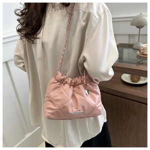 Borsa a secchiello rosa trapuntata con catena in un caffè per un look casual e chic