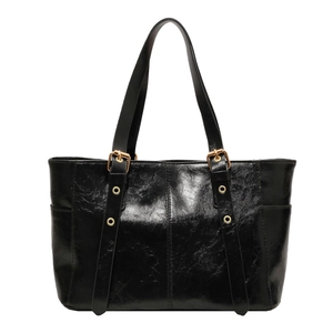 Bolso tote negro brillante con herrajes dorados y bolsillos laterales en fondo blanco