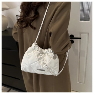 Sac seau matelassé blanc avec chaîne argentée porté en bandoulière sur une silhouette