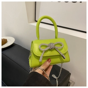 Detalle de minibolso de cuero verde lima con lazo de diamantes y correa de cadena de plata
