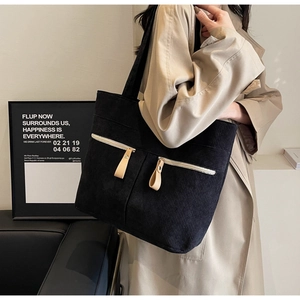 Close-up of black corduroy tote bag with dual zipper pockets and retro ribbed texture
