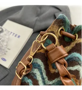 Detalle de bolso de punto bohemio con herrajes dorados y adornos de cuero de lujo