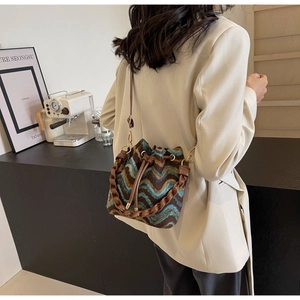 Detalle del bolso tipo saco con textura ondulada y cordón de cuero marrón con cadena