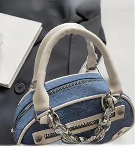 Detail of blue denim handbag with white leather trim and chunky silver chain accent