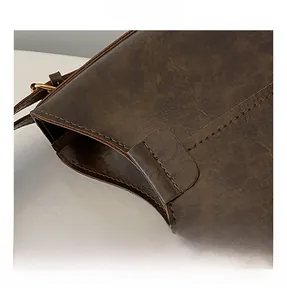 Gros plan sur la texture cuir vintage et les coutures renforcées d'un grand cabas