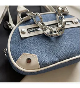 Detail of blue denim shoulder bag with white leather trim and chunky silver chain