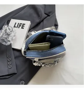 Detail of blue denim handbag with white leather trim and large silver metal chain